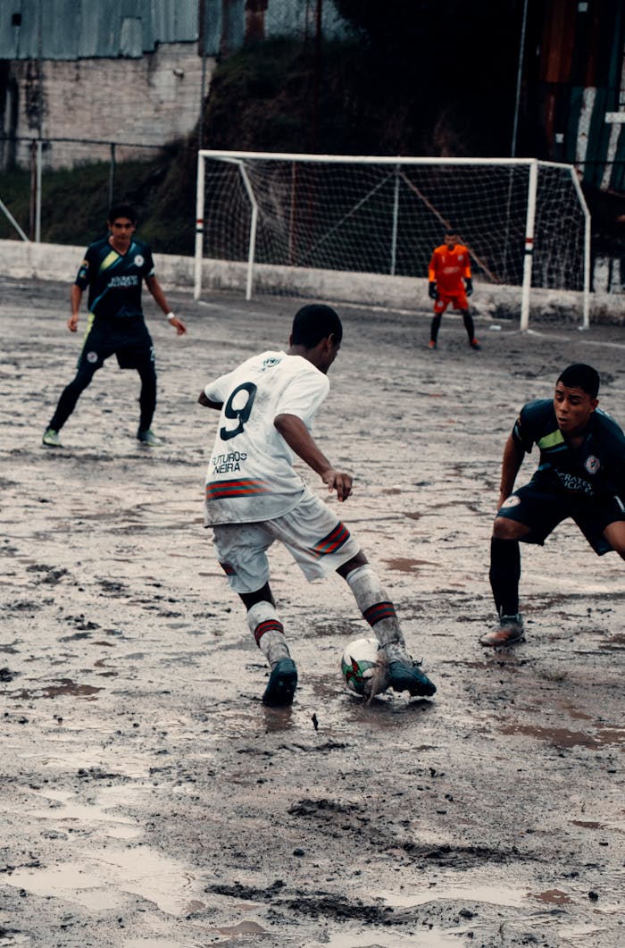 Young soccer players compete intensely on a muddy field in Neira, Colombia.